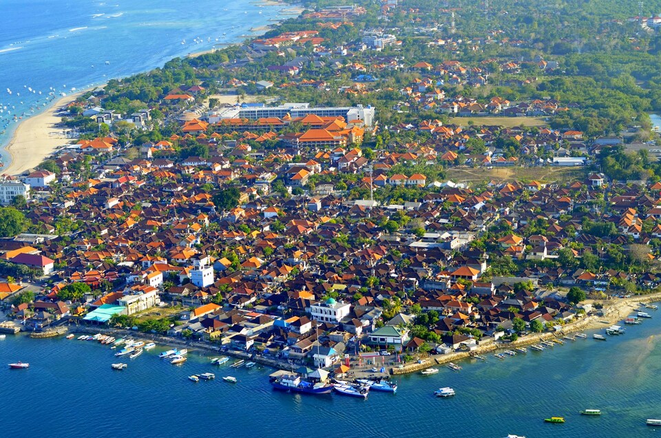 An aerial view of Bali island, showing lots of boats, villas, resorts and hotels 