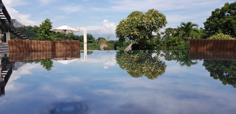 A glass table with sky's reflection and two chairs at a resort 