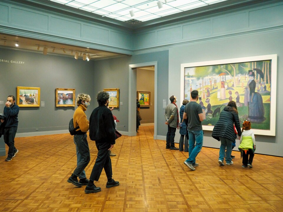 A group of people standing in a museum looking at paintings